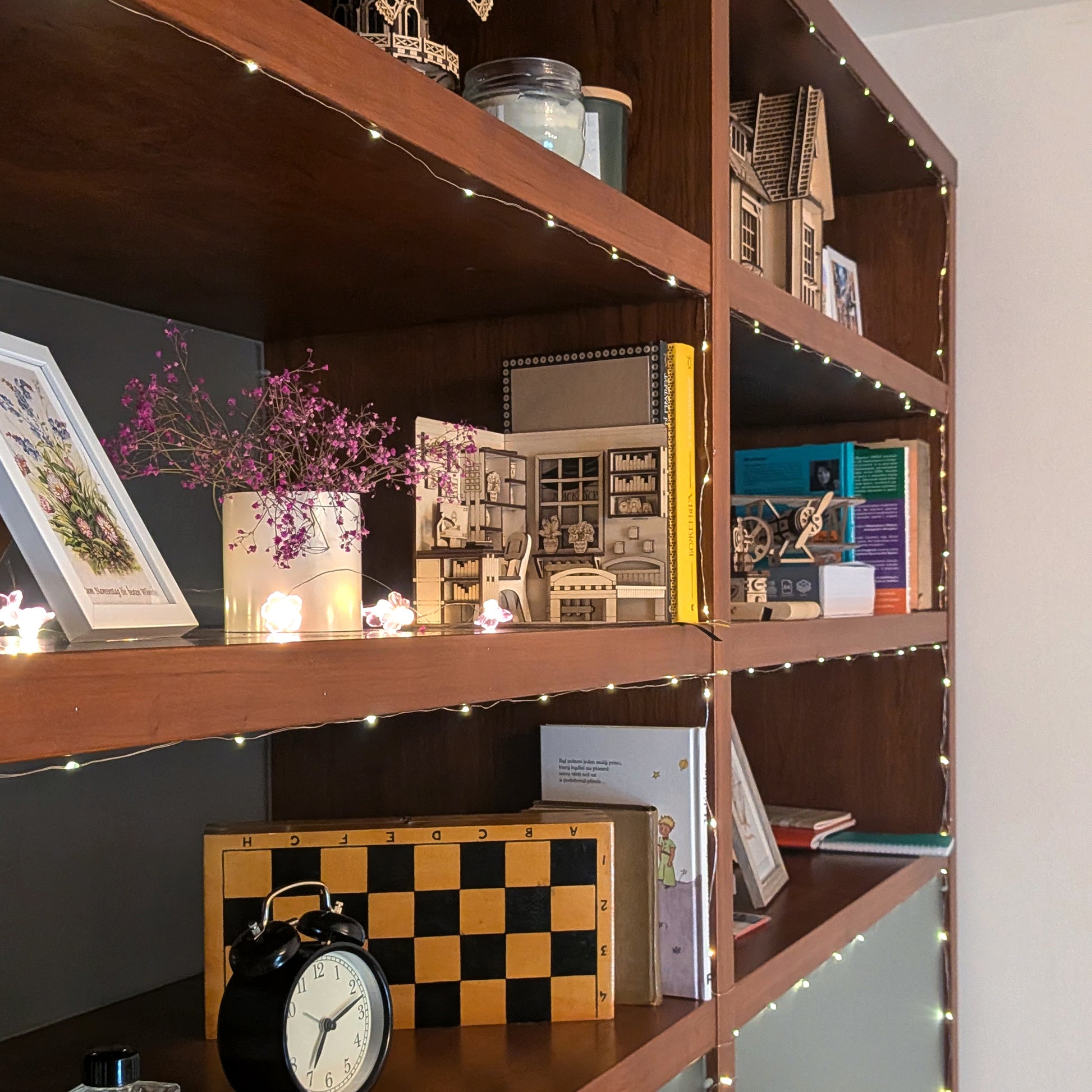 Wooden bookshelf with decorative items and string lights and laser cut book nook model