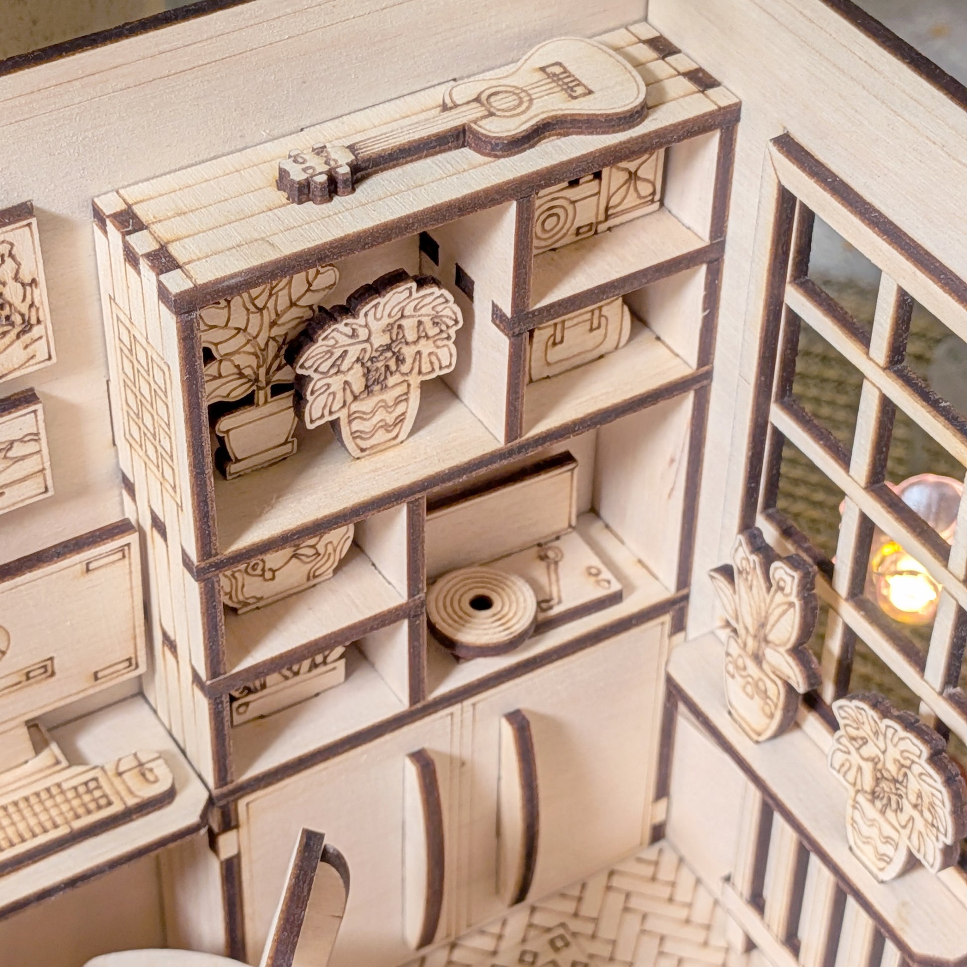 Miniature wooden bookshelf with guitar, houseplants and decor inside a cozy dollhouse bedroom diorama, laser cut file template for book nook craft