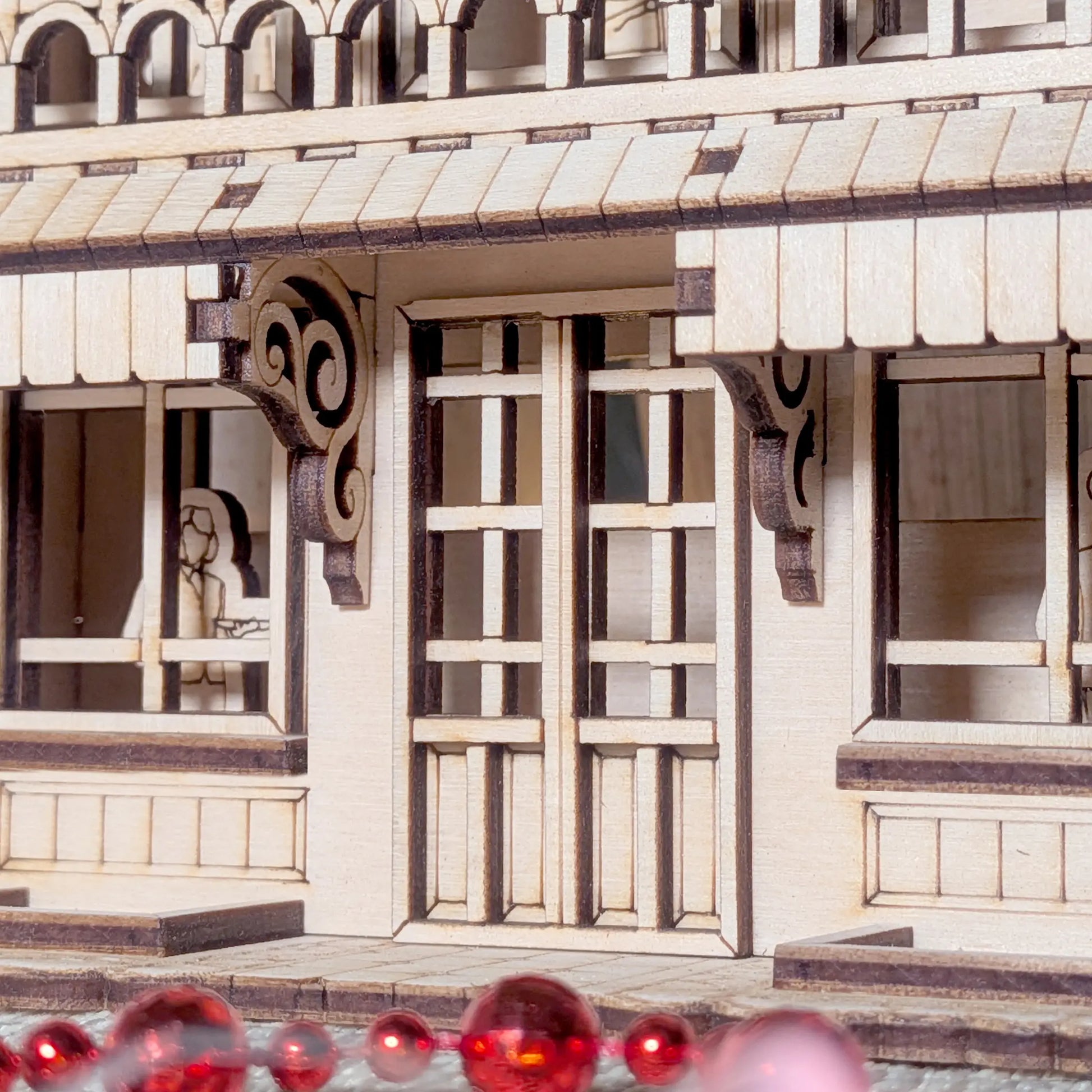 Detailed close-up of the ground floor shop doors and windows of a miniature house made of laser cut plywood