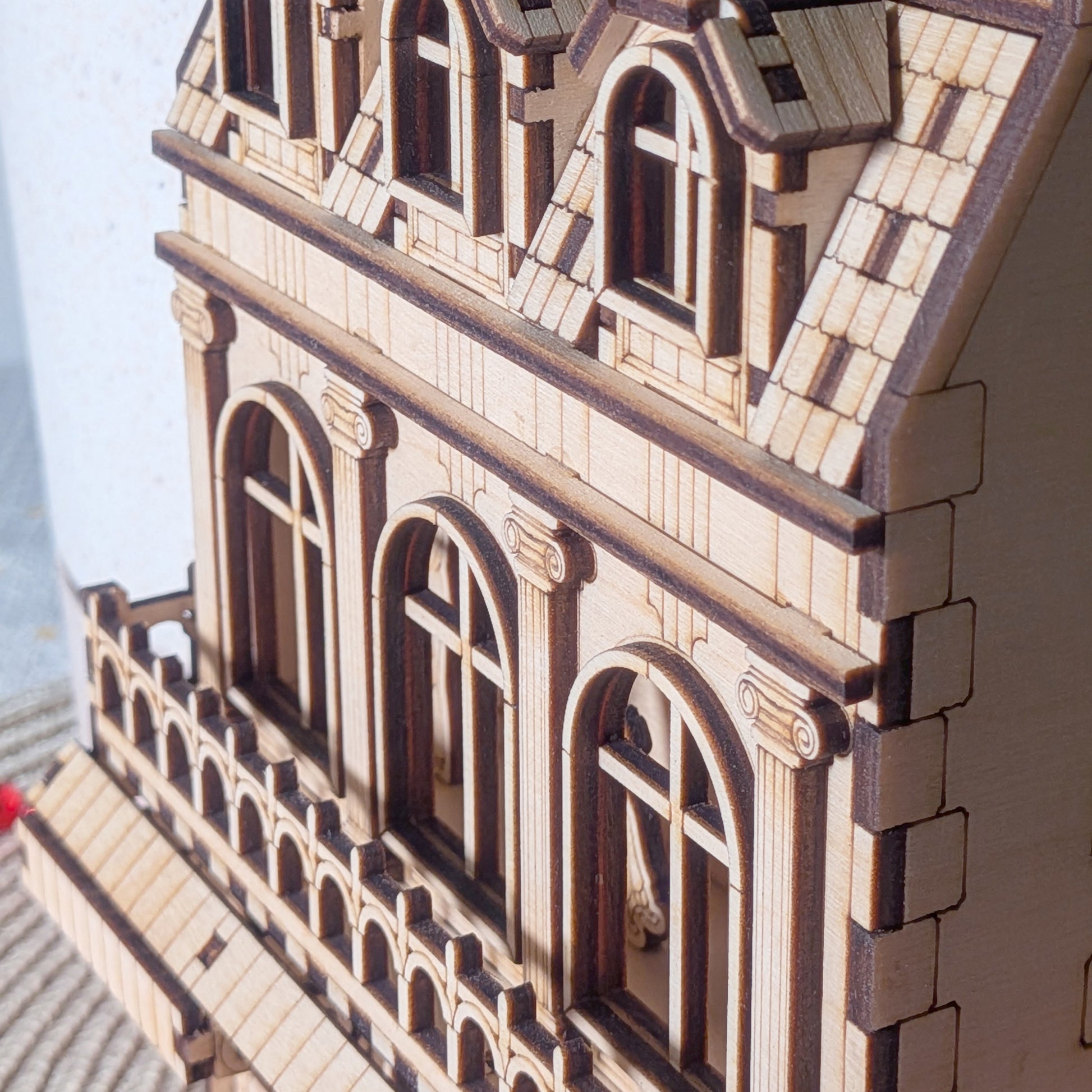 Side angle of the laser cut wooden book nook showing upper arched windows, balcony trim, and dormer windows on the roof