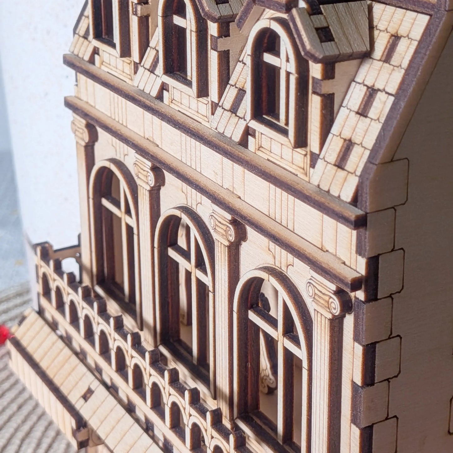Macro close-up showing layered details, columns, and windows of an architectural miniature in laser cut plywood
