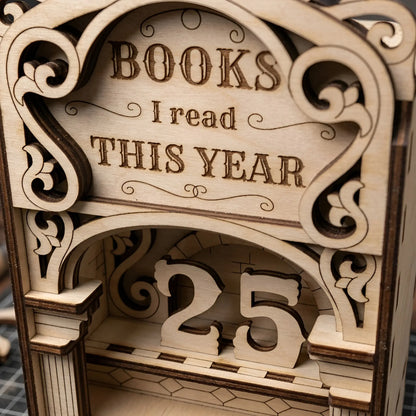 Close-up of a laser cut wooden book reading tracker with engraved lettering, decorative scrollwork, arch design, and removable number pieces showing 25 books read this year.