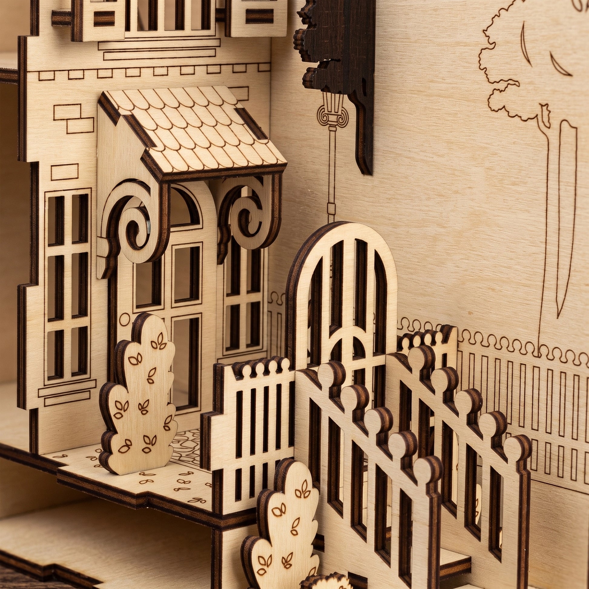 Close-up of a laser-cut birch plywood romantic house book nook front porch, stairs, fence, and dark burnt edges.