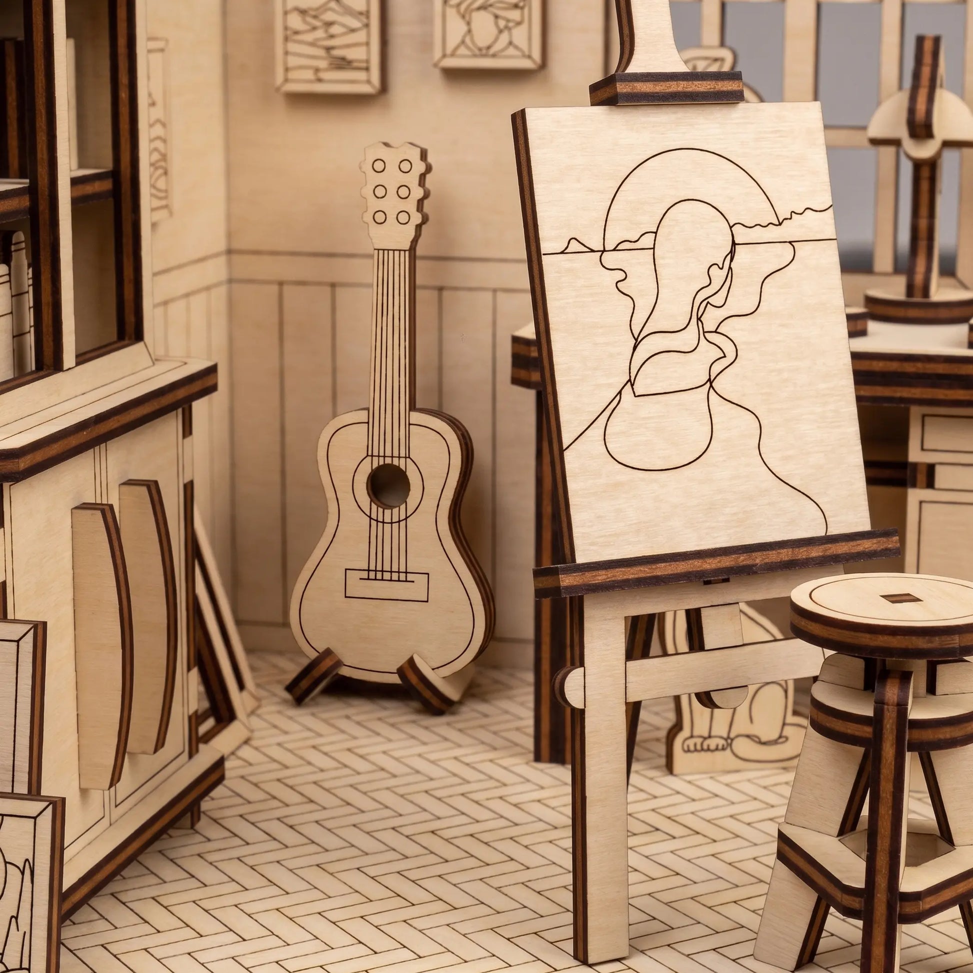 Close-up of an easel with a canvas engraving and a guitar inside an artist room kit made of laser cut plywood layers.