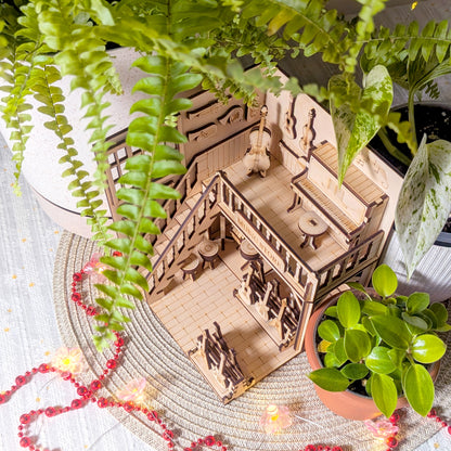 Top angled view of a laser cut wooden music store diorama showing the upper piano area, guitars and interior details surrounded by green plants and string lights