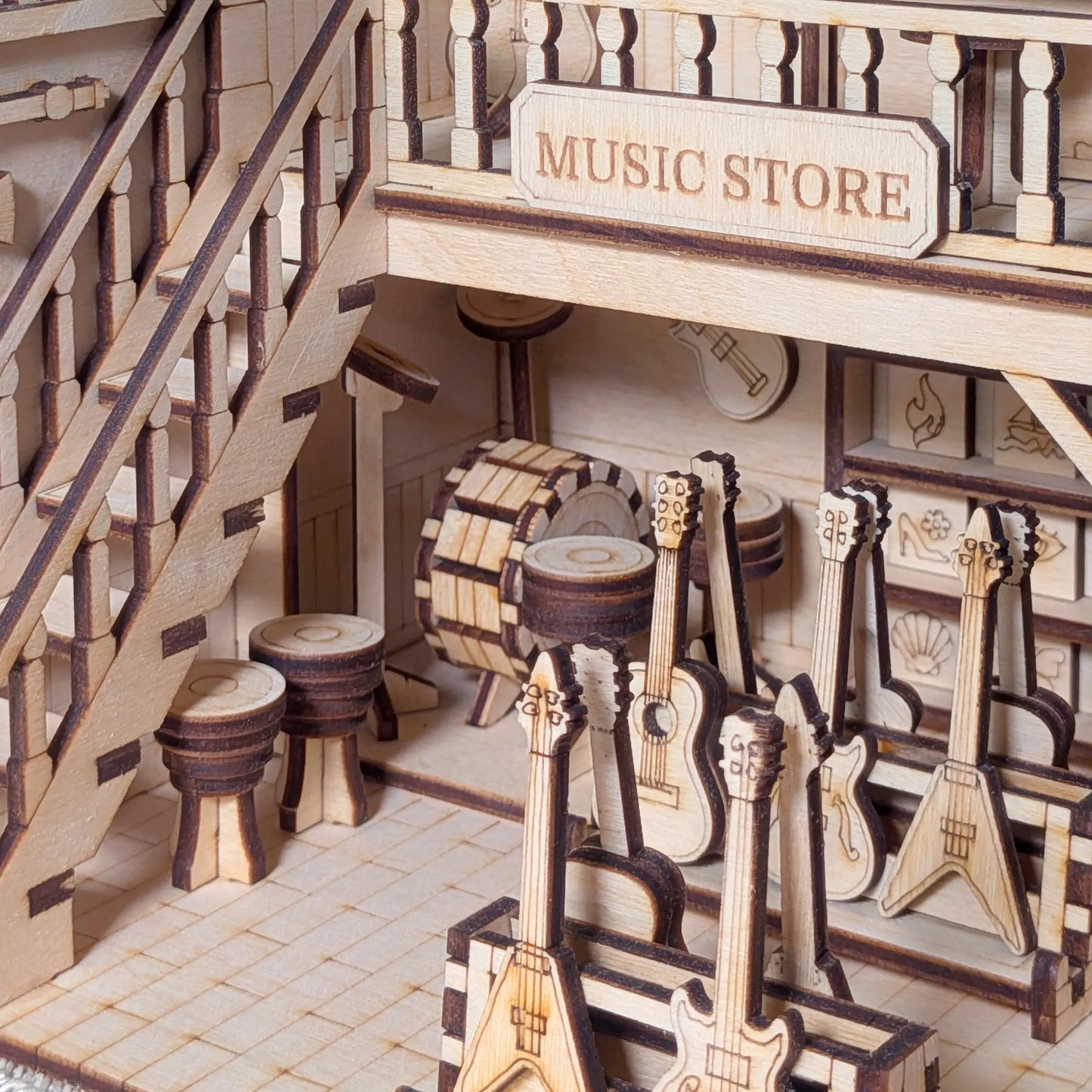 Ground floor view of a laser cut plywood miniature music shop, showcasing racks of tiny guitars and a bongo drum.