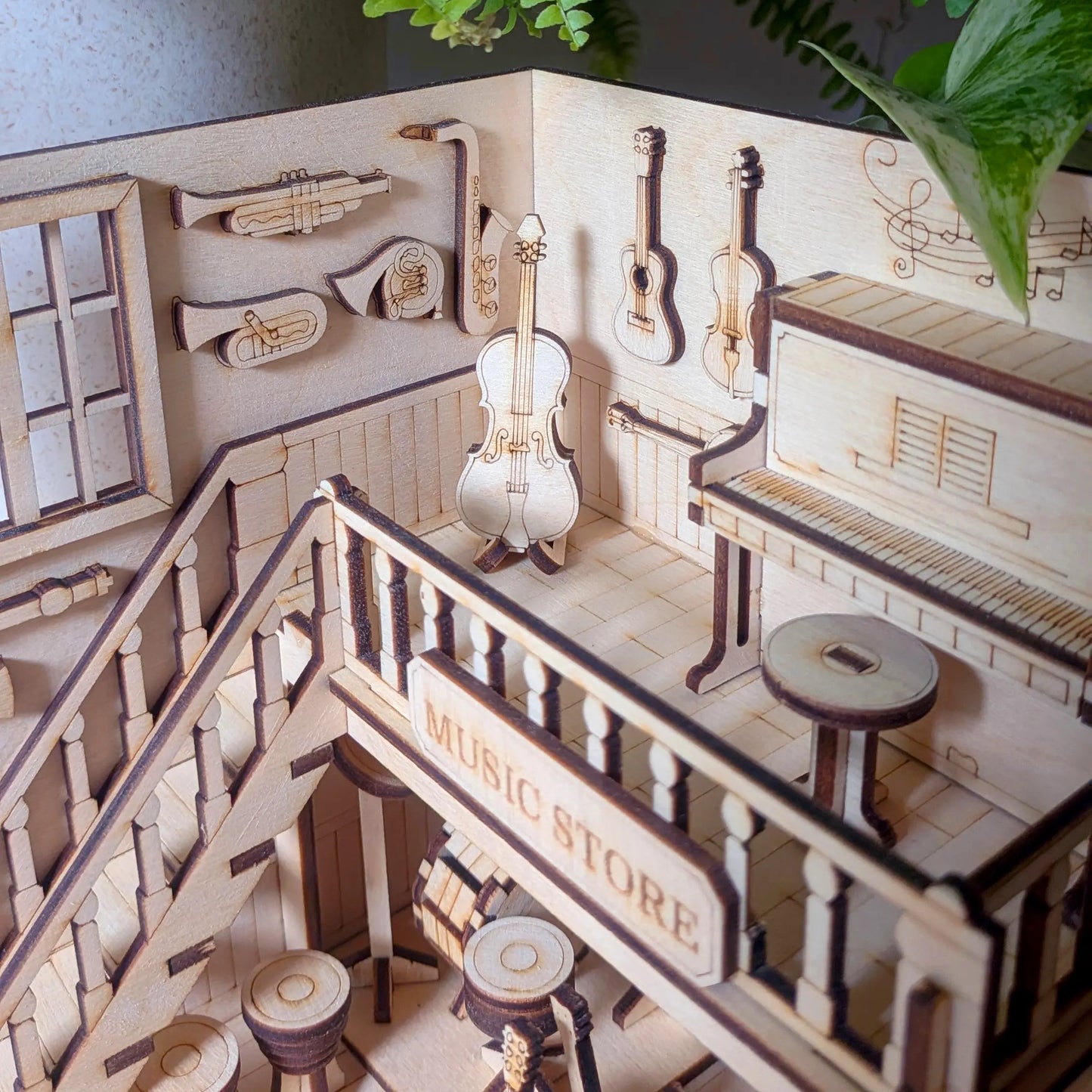 Upper balcony view of a laser cut plywood miniature instrument shop, featuring a piano and wind icons on the wall.