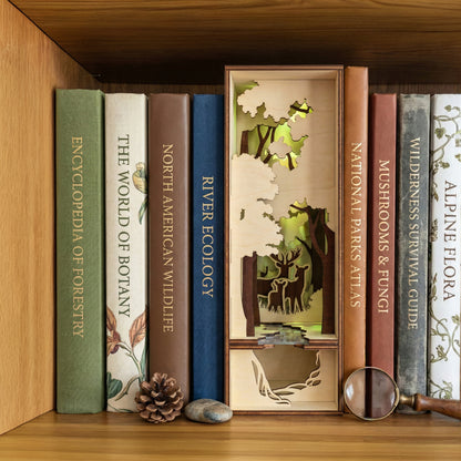Detailed Book Nook Nature insert made of laser cut wood depicting trees and wildlife, set between nature books on a wooden bookshelf background.