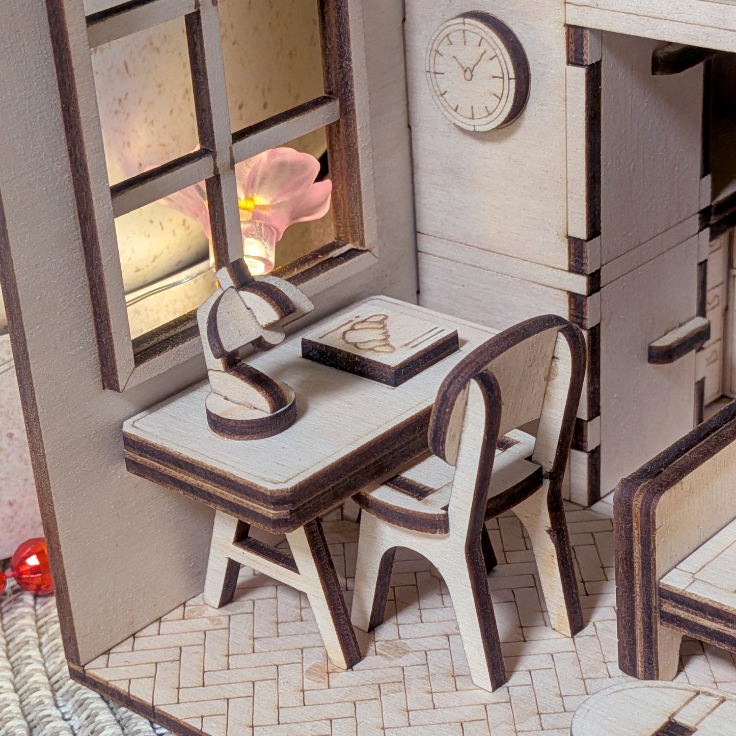 Miniature wooden desk and chair inside a cozy small room, made from layered plywood pieces. Designed as a laser cut template with tiny lamp, book, and window detail
