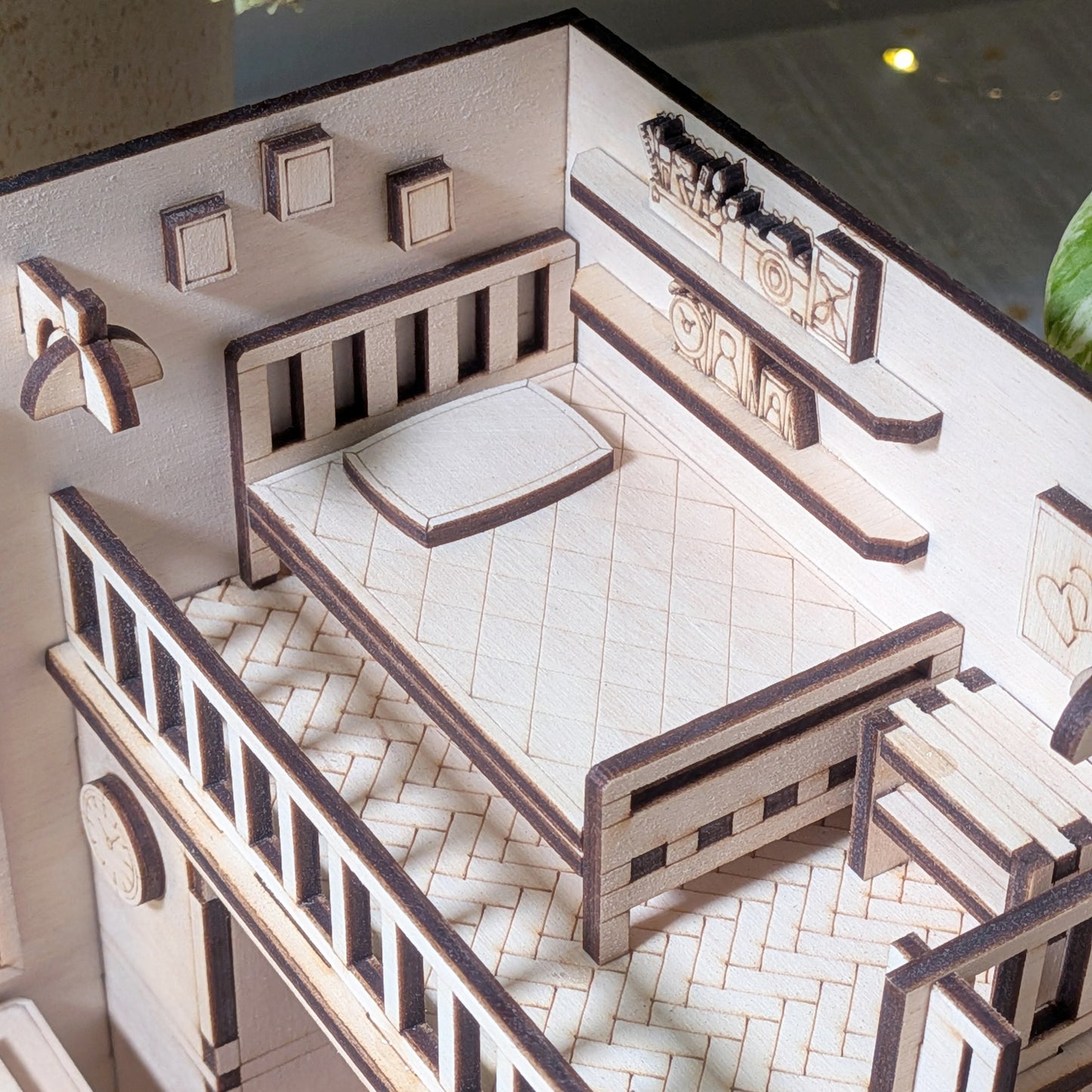 Close-up of the miniature loft bedroom with a wooden bed, pillow and wall shelves. Part of a laser cut wooden dollhouse room book nook diorama template