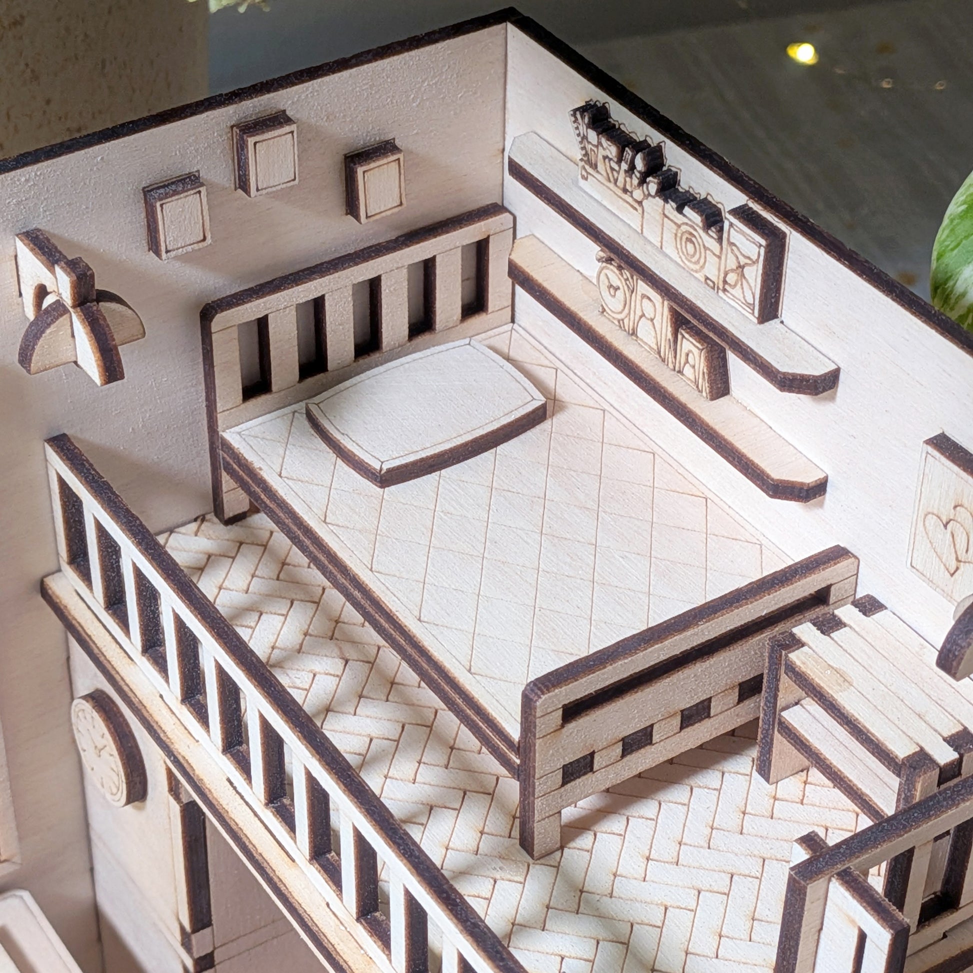 Close-up of the miniature loft bedroom with a wooden bed, pillow and wall shelves. Part of a laser cut wooden dollhouse room book nook diorama template