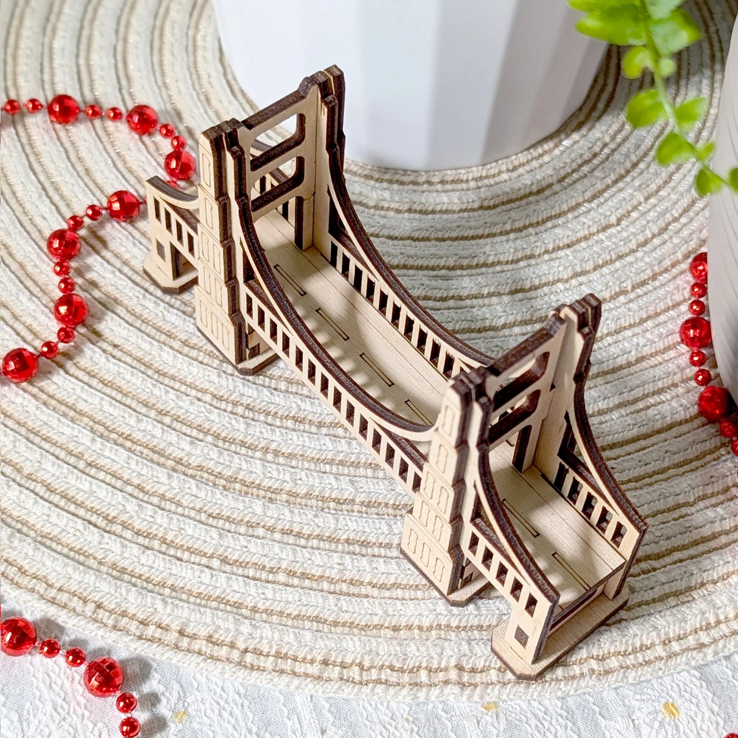 Top down angle of a miniature architectural bridge of laser cut plywood, highlighting the textured plank walkway surface