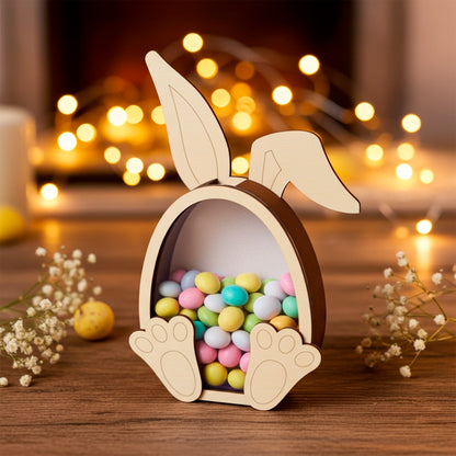 Laser cut plywood wooden bunny coin bank or candy box, filled with colorful pastel Easter chocolate eggs, sitting on a rustic table with soft, golden fairy lights and baby's breath flowers in the warm background.