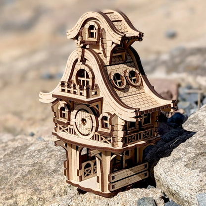 Whimsical laser cut plywood bunny house model with small carrot details resting on a vibrant green mossy rock in the woods.