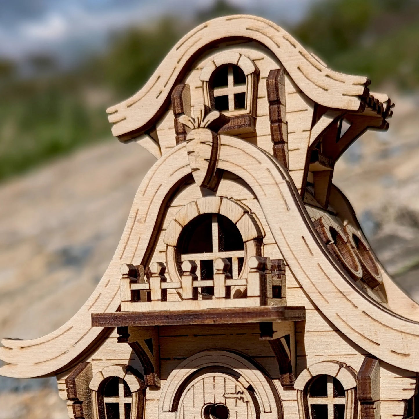Detailed macro shot of a cute laser cut plywood bunny house showing burnt wood edges on a sunlit textured stone surface.