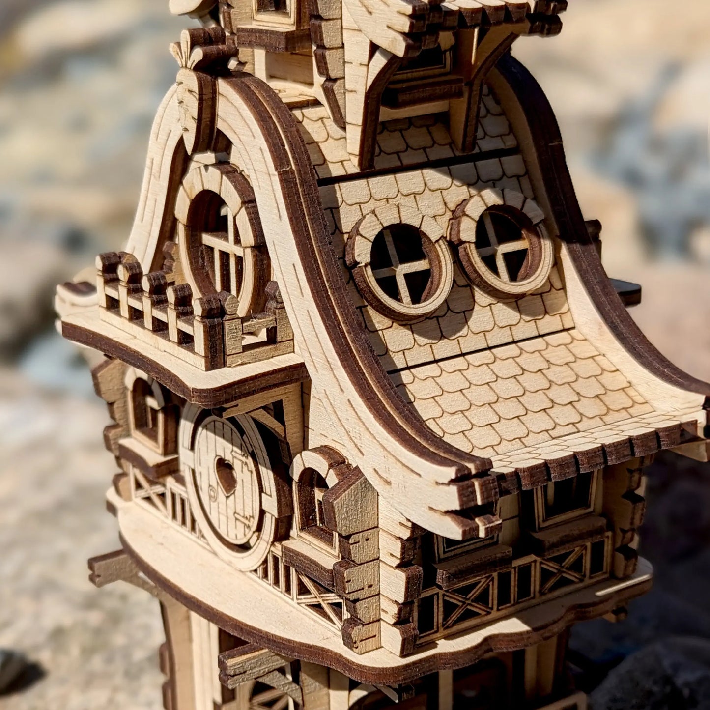 Close-up of a laser cut plywood bunny house puzzle staged outside in fresh green grass next to a bright yellow dandelion.