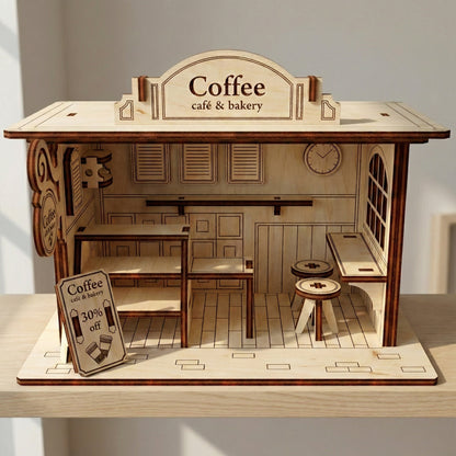 Frontal view of a laser cut plywood miniature coffee house. The symmetrical design showcases etched wall panels, a service counter, and a rounded "Coffee" roof sign. The intricate assembly highlights the natural texture of the plywood material.