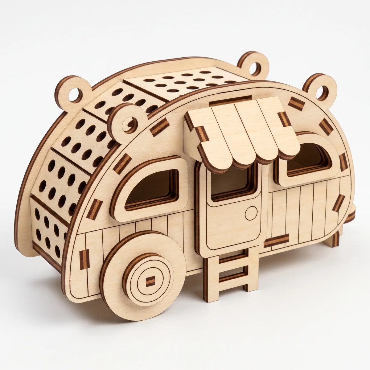 Laser cut plywood teardrop camper ornament with striped window awning, roof vents, and door steps on white background.