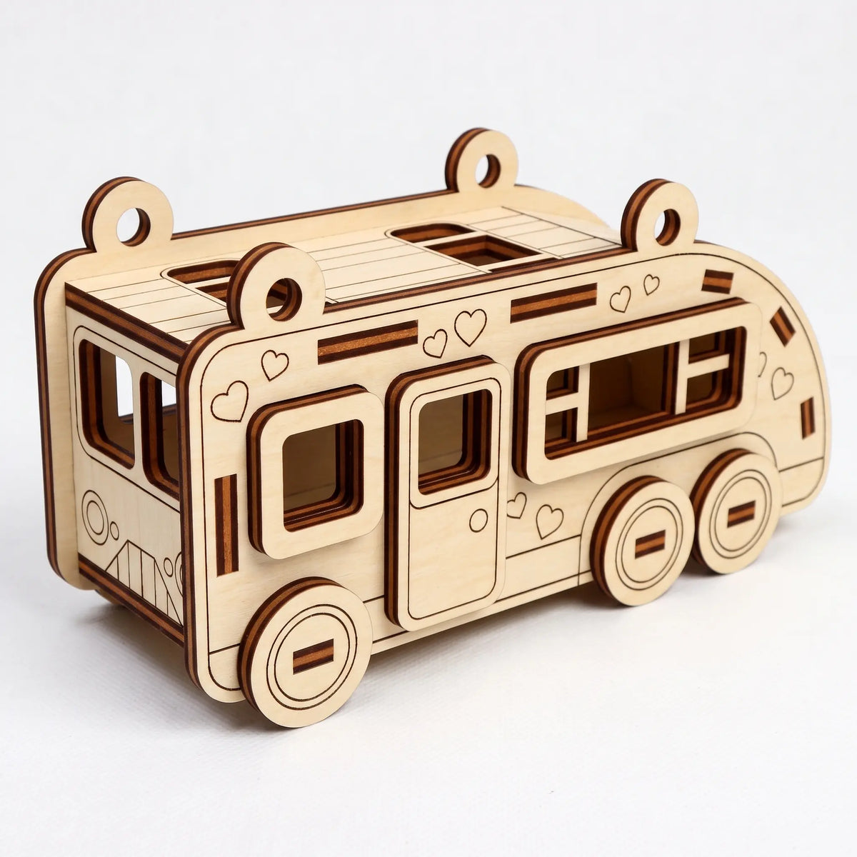 Laser cut plywood motorhome RV model featuring engraved little hearts and side windows sitting on a white background.
