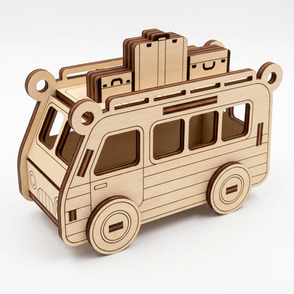 Natural laser cut plywood travel bus model carrying layered suitcases on top roof rack against plain white backdrop.