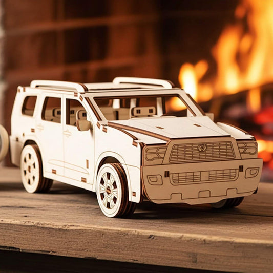 Front three-quarter view of a laser cut wooden plywood 3D puzzle on a wooden surface. Features a detailed front grille, round headlights, and precise plywood layers. Warm background with a crackling fireplace and a white coffee mug