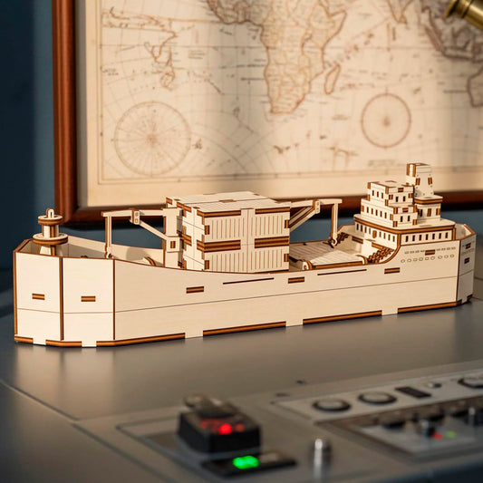 A light wooden plywood laser cut model of a modern container ship with detailed cargo boxes on deck, displayed on a futuristic control panel or desk with illuminated buttons, with a framed vintage world map and telescope visible in the background