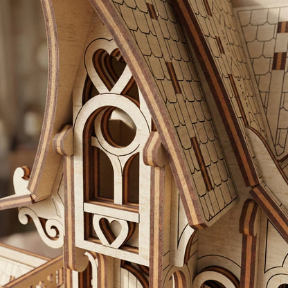 Close-up of a wooden model laser cut house with detailed roof and window design.