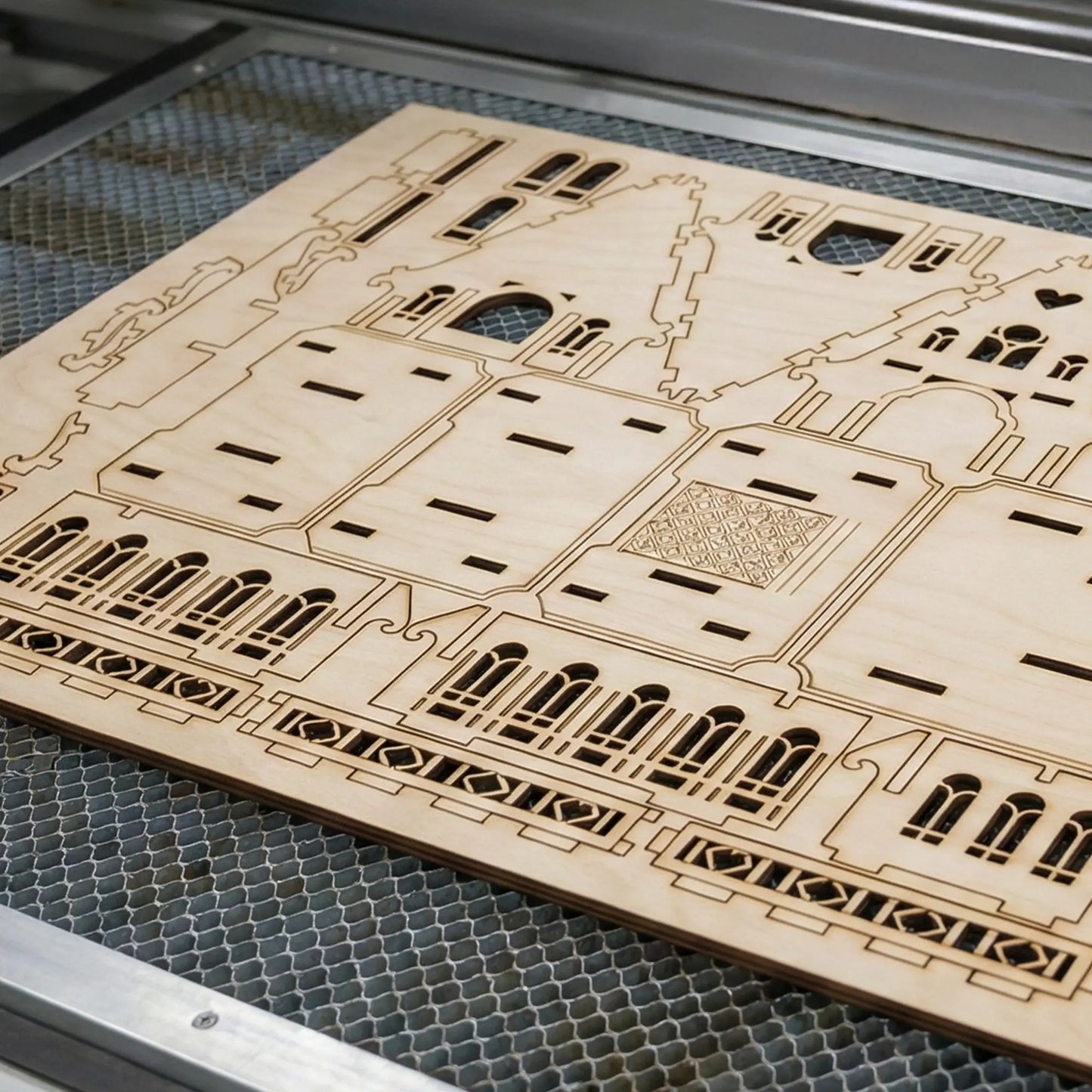Wooden laser-cut architectural model on a metal grid laser cutter surface