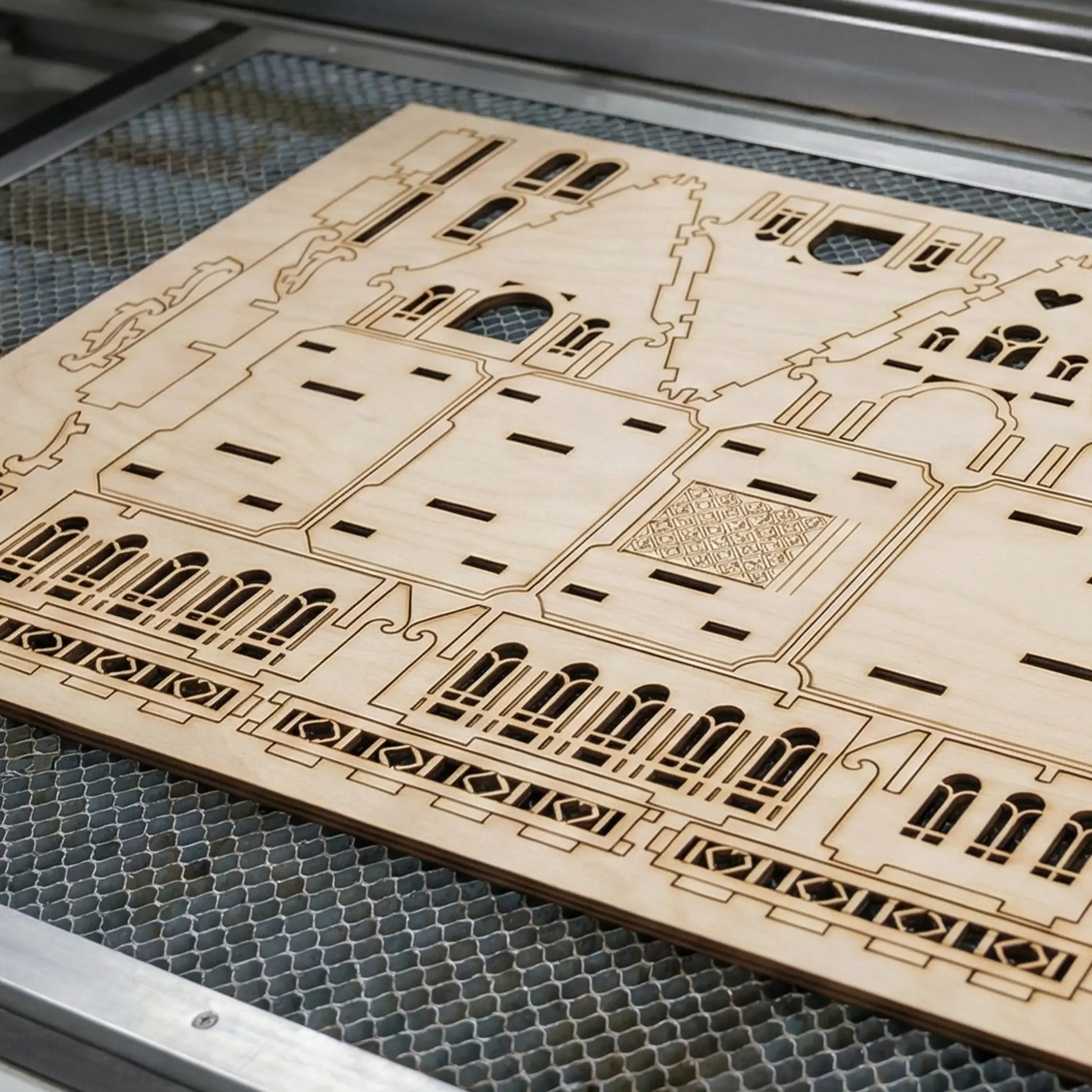 Wooden laser-cut architectural model on a metal grid laser cutter surface
