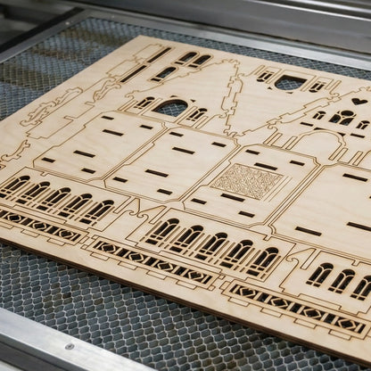 Wooden laser-cut architectural model on a metal grid laser cutter surface