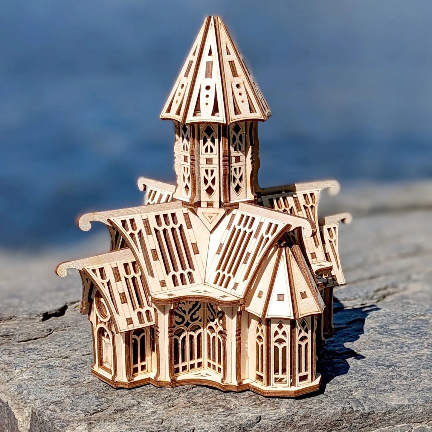 Laser cut plywood fantasy castle miniature catching bright sunlight on a rock surface
