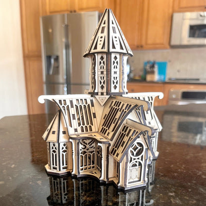 Assembled laser cut plywood gothic palace model with dark burnt edges placed on a reflective kitchen counter top.