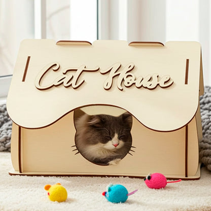Laser cut wooden plywood Cat House featuring a classic peaked roof design and a decorative cat-shaped entrance cutout. The lightweight plywood structure, suitable as a DIY kit, includes round side windows and an engraved "Cat House" script on the front roof panel. Close-up on a white background.
