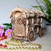 Wooden laser cut nomad wagon model of a decorative carriage with intricate designs, surrounded by flowers and beads on a light surface.