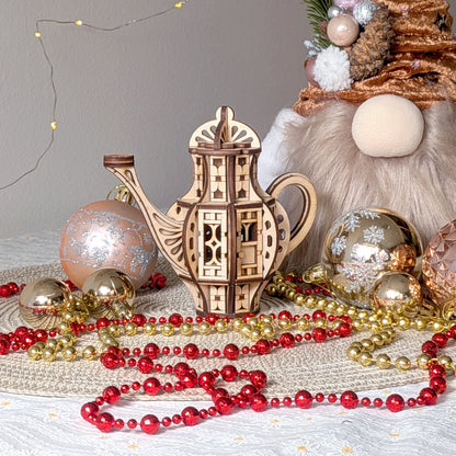 Laser cut wooden teapot fairy house displayed in a festive scene with Christmas ornaments, golden and red bead garlands, and soft lighting.