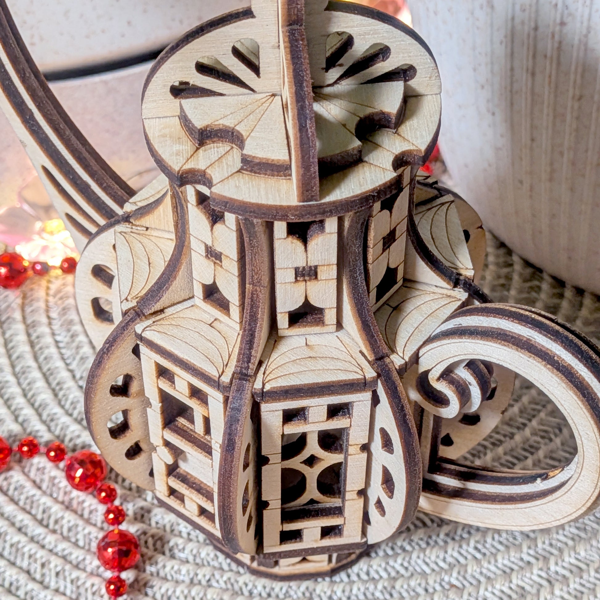 Close-up view of the curved handle and detailed layered wood structure of the laser cut teapot fairy house, highlighting intricate cut patterns.