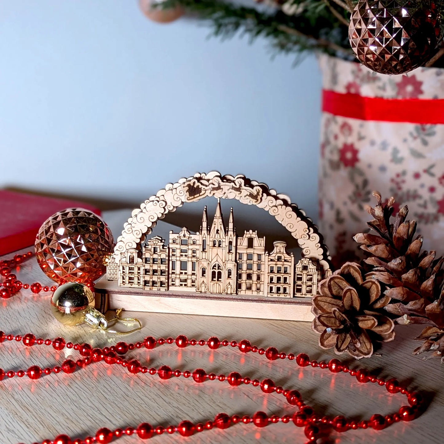 Wide festive product photography of a cozy tabletop winter village arch display beautifully made from fine laser cut plywood.