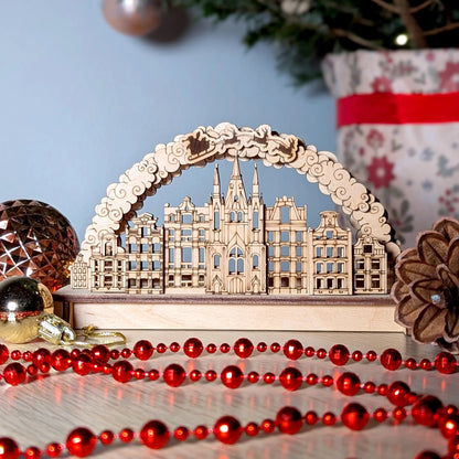A mid-range front view focusing on a 3D Christmas village arch puzzle styled with festive red beads and laser cut plywood