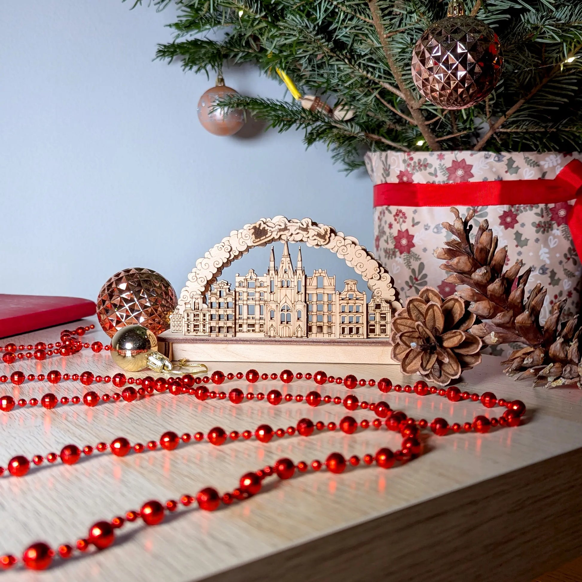 Wide holiday home table display featuring a 3D winter village scene arch with a Christmas tree made of laser cut plywood.