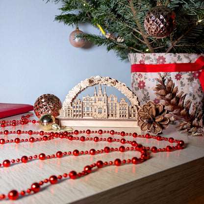 Wide holiday home table display featuring a 3D winter village scene arch with a Christmas tree made of laser cut plywood.