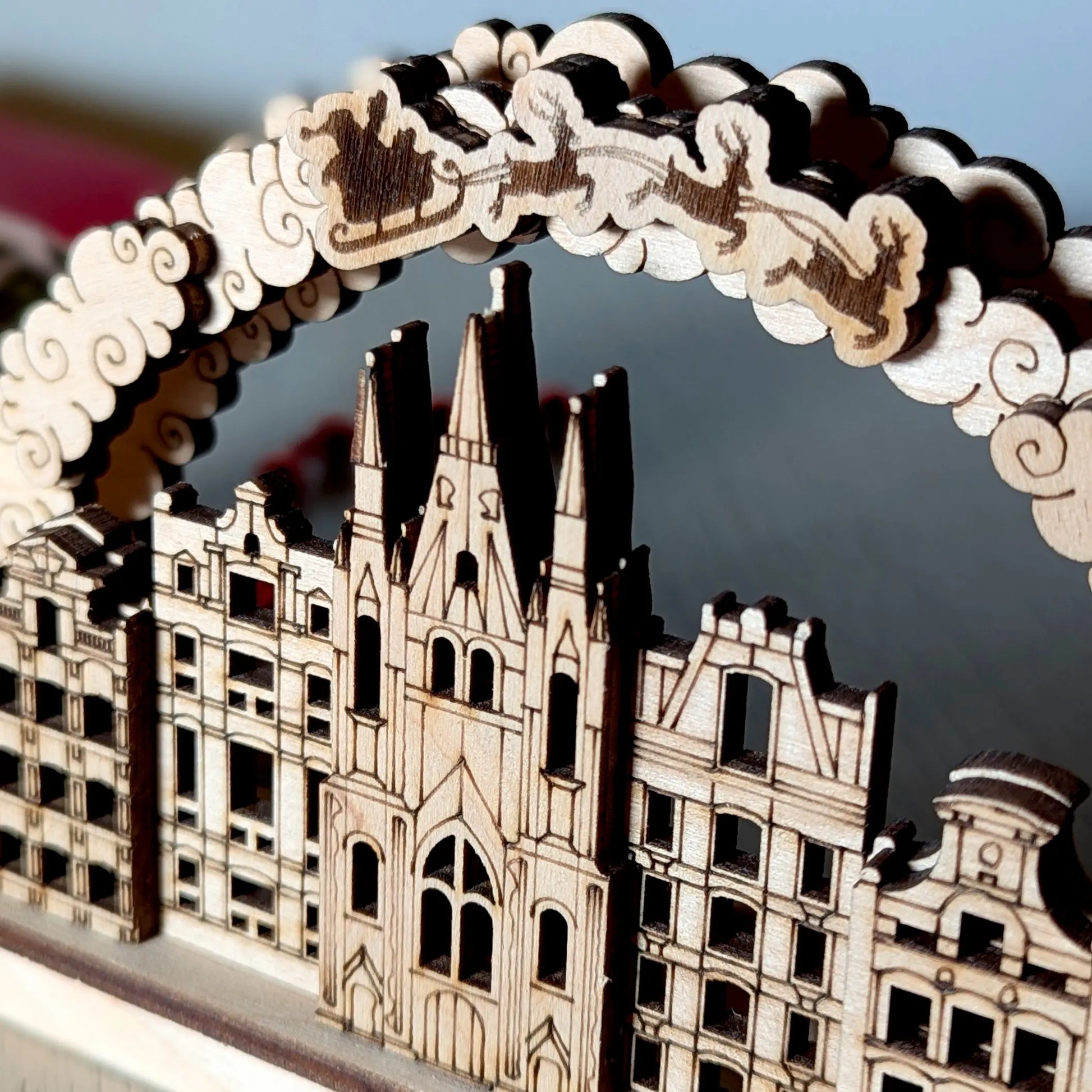 Detailed macro close-up of engraved Santa sleigh and cathedral facade on a Christmas arch made from fine laser cut plywood.