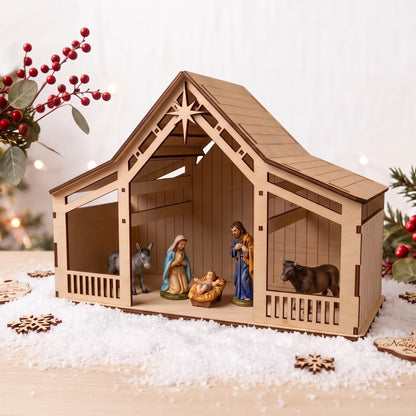Side view of laser cut plywood nativity stable with ceramic figures set on artificial snow with red berries.