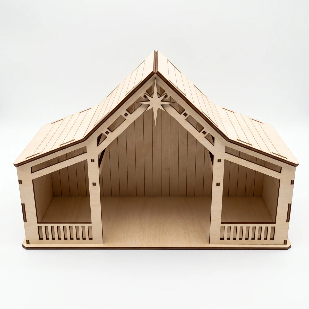 Front direct shot of empty laser cut plywood nativity stable showing open stalls isolated on white background.