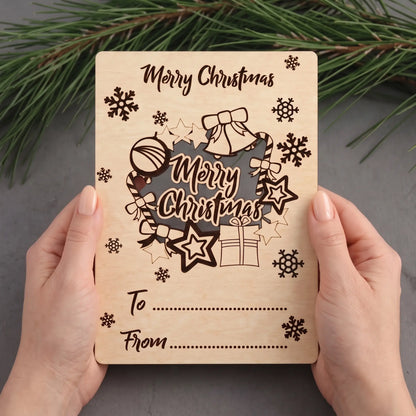 Hands hold laser cut plywood holiday greeting postcard with pop-out wreath cutout over gray table and pine.