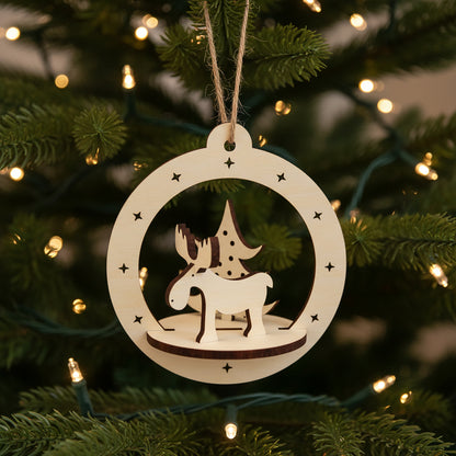 Intricate laser cut Christmas Deer Ornament featuring a cute reindeer with antlers and holiday tree in a hanging round frame with star accents, set against a warm lighted Christmas tree background.