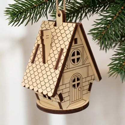 Side angle of hanging laser cut plywood fairytale cottage ornament with chimney and round door on Christmas pine tree.