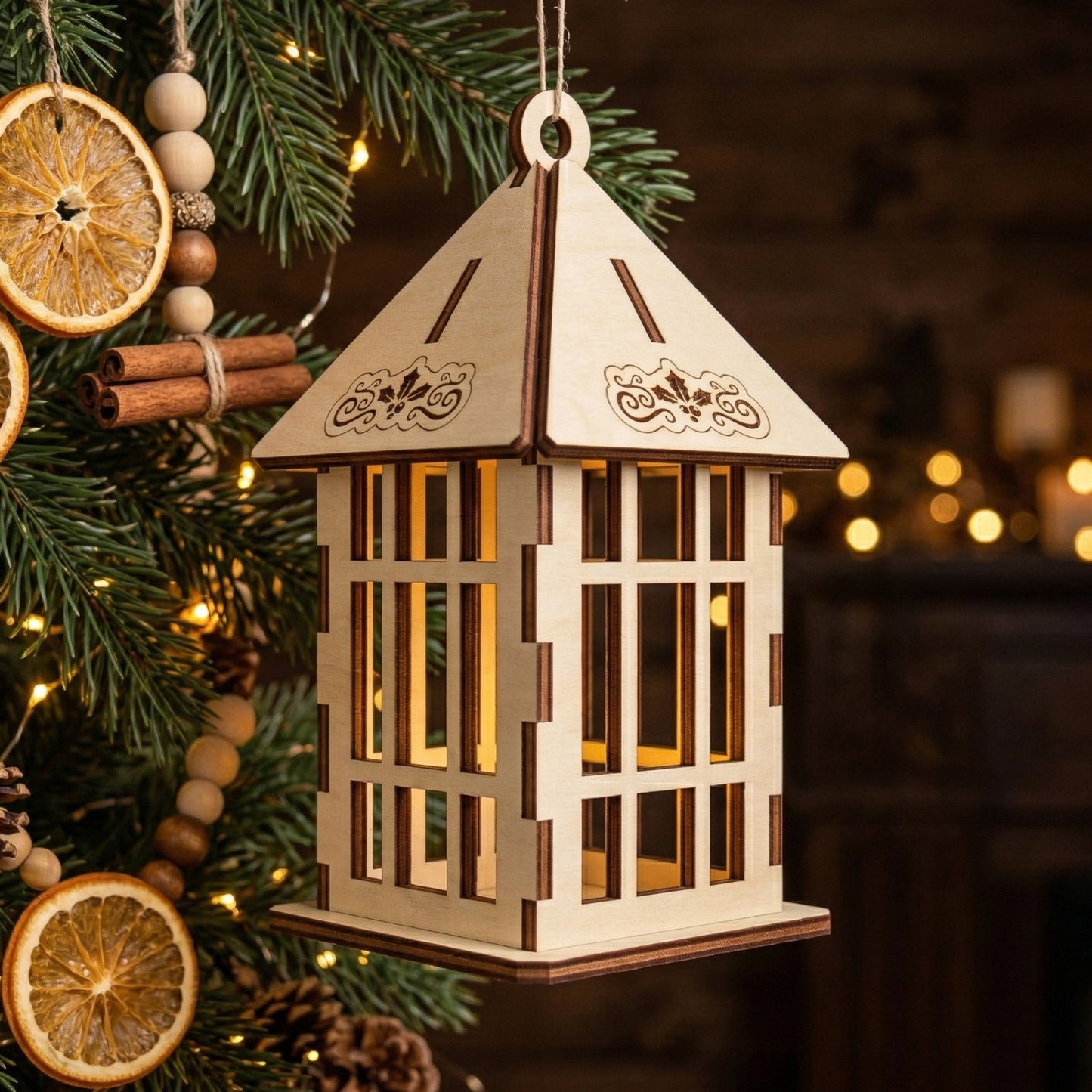 A handcrafted wooden 3D lantern ornament glowing warmly from within. Features precise laser-cut windows and a holly-engraved roof. Posed on a rustic Christmas tree decorated with dried orange slices, cinnamon sticks, and wooden beads.