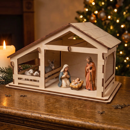 Side view of laser cut plywood nativity stable with ceramic figurines on wooden table by candle light.