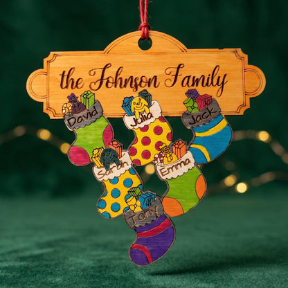 A personalized laser cut Christmas ornament shaped like a family name sign above four colorful hand-drawn stockings. 