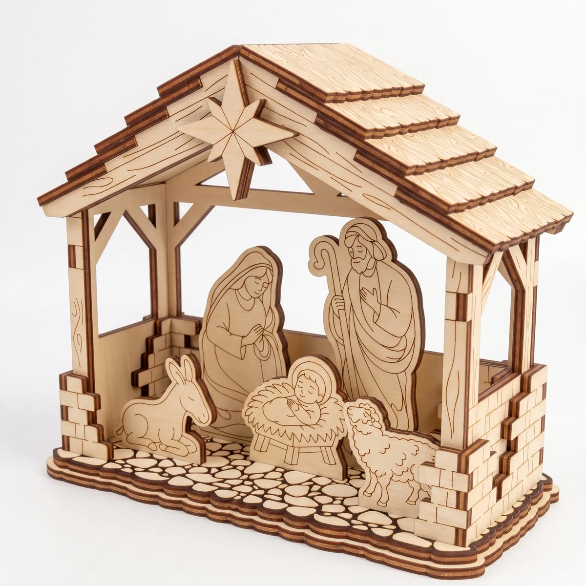 Angle view of laser cut plywood Nativity stable scene with Holy Family and animals on cobblestone base over white backdrop.